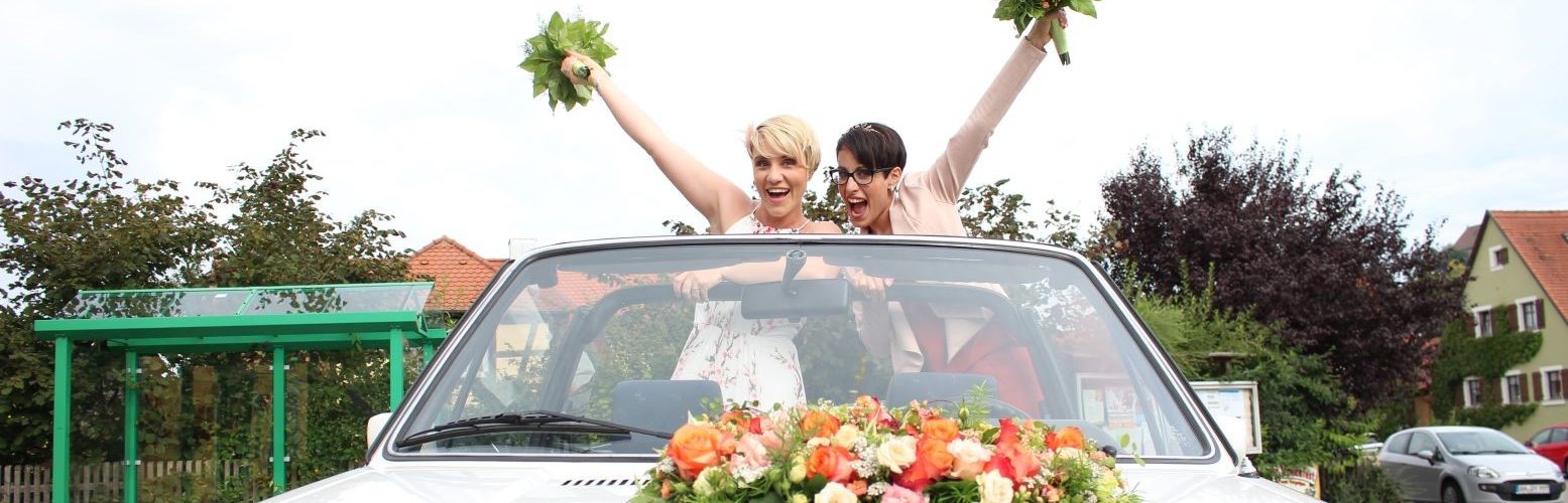 Zwei Frauen halten Brautstrauß in die Luft